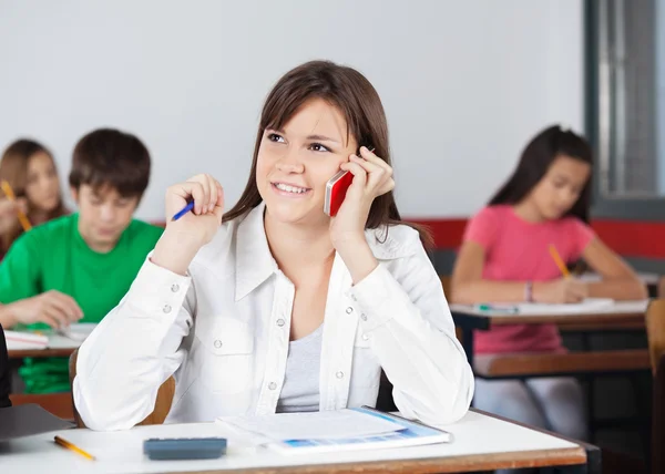 Studentin schaut weg, während sie Handy benutzt — Stockfoto