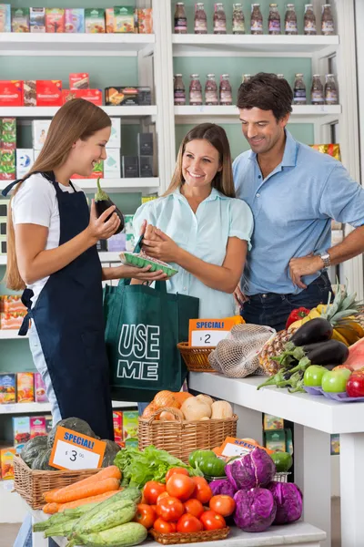 Försäljare visar vegetabiliska packet till par — Stockfoto