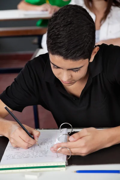 Student kopiert vom Spickzettel am Schreibtisch — Stockfoto