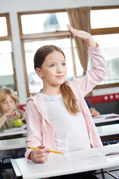 Schülerin schaut weg, während sie im Klassenzimmer die Hand hebt — Stockfoto