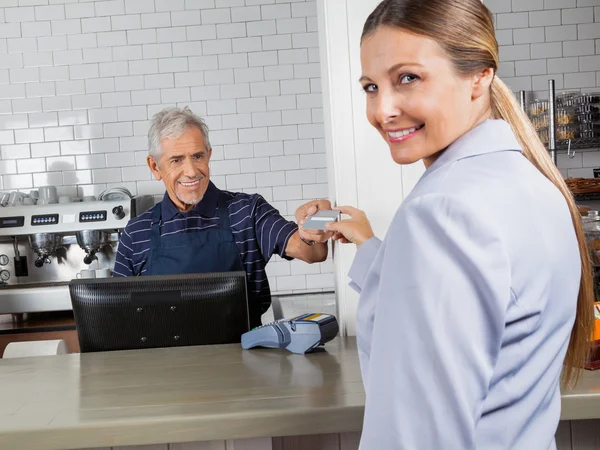 Cliente feminino fazendo pagamento através de cartão de crédito na loja — Fotografia de Stock