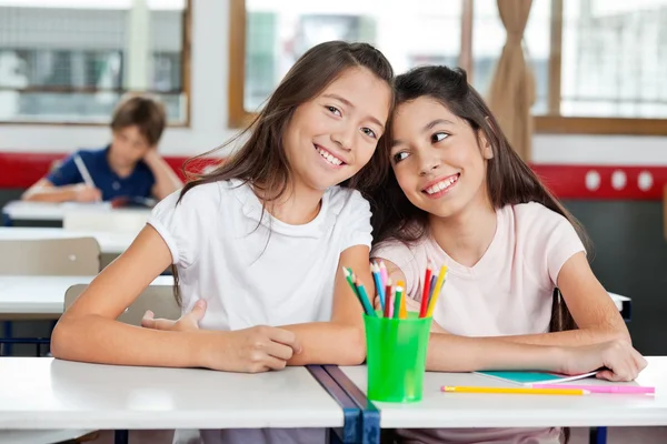 Liseli kızlar sınıfta masasındaki kadın arkadaşıyla oturan — Stok fotoğraf