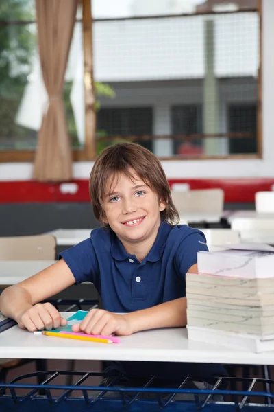 Skolpojke med böcker och världen vid skrivbord — Stockfoto