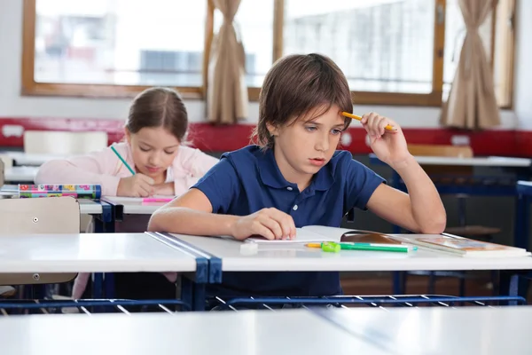 Nachdenklicher Junge sitzt am Schreibtisch — Stockfoto