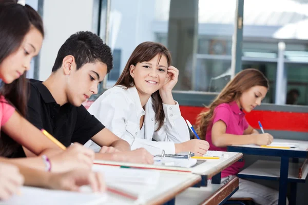 Ragazza adolescente con gli amici che scrive alla scrivania — Foto Stock