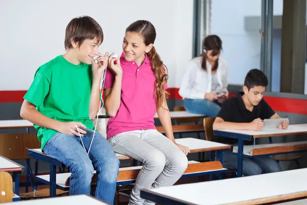 Adolescent garçon et fille écoute musique dans salle de classe — Photo