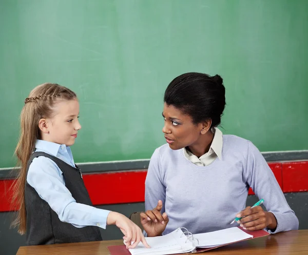 Učitel při pohledu na sebe na stůl a školačka — Stock fotografie