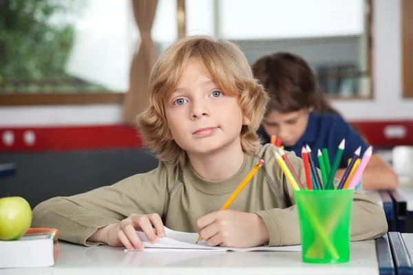 Portret van schooljongen schrijven in boek bij receptie — Stockfoto