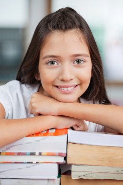liseli kızlar sınıfta kitap yığını üzerine eğilerek