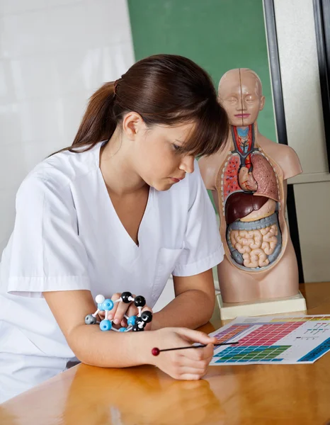 Estudante com papel de leitura de estrutura molecular na mesa — Fotografia de Stock