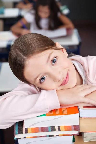 Feliz colegiala apoyándose en pila de libros — Foto de Stock