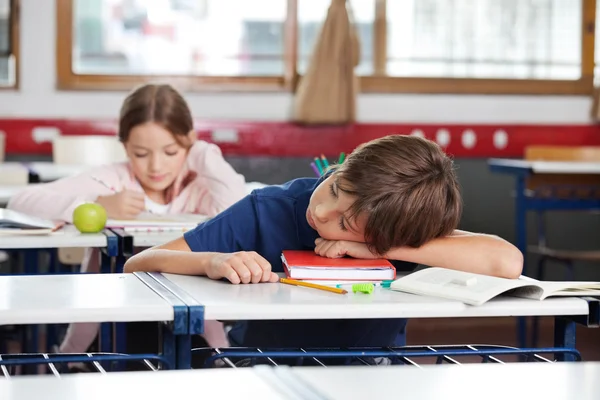 Menino dormindo na mesa na sala de aula — Fotografia de Stock