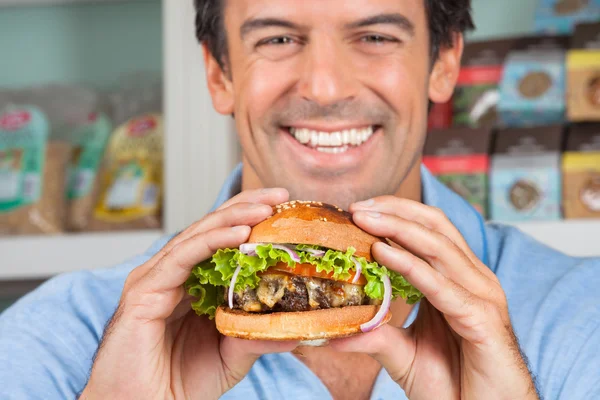 Hombre feliz sosteniendo Bugger en tienda de comestibles —  Fotos de Stock