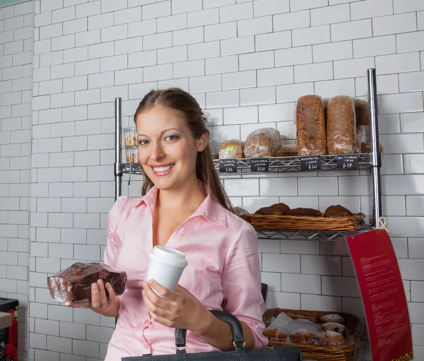 Frau hält Kuchen und Kaffeetasse im Supermarkt — Stockfoto