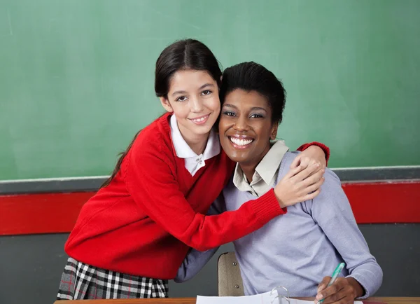 Glückliches Schulmädchen umarmt Professor im Klassenzimmer — Stockfoto