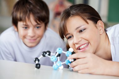 Happy Teenage Boy And Girl Looking At Molecular Structure