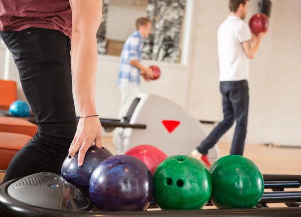 Homme cueillette boule de bowling avec des amis en arrière-plan — Photo