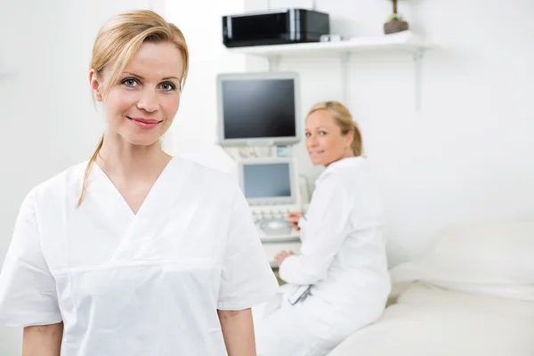 Joyeuse gynécologue féminine avec collègue en arrière-plan — Photo