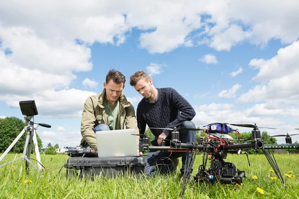 Técnicos trabajando en el ordenador portátil por UAV en el parque —  Fotos de Stock