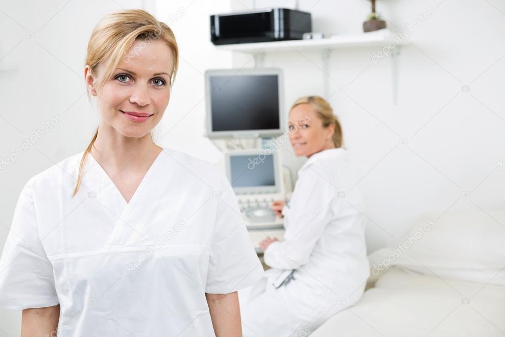 Happy Female Gynecologist With Colleague In Background