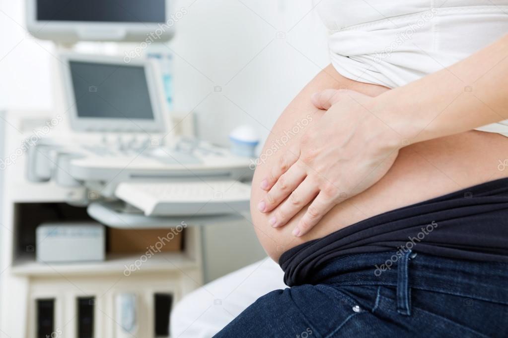 Pregnant Woman Touching Her Stomach In Clinic