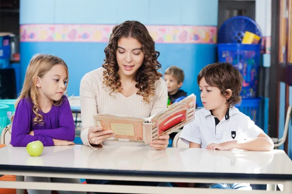 Lehrerin liest Buch, während Kinder ihr zuhören — Stockfoto