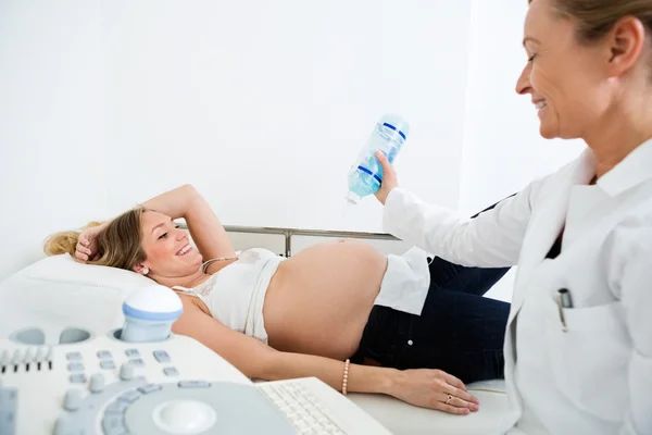 Médico aplicando gel na barriga da mulher grávida — Fotografia de Stock