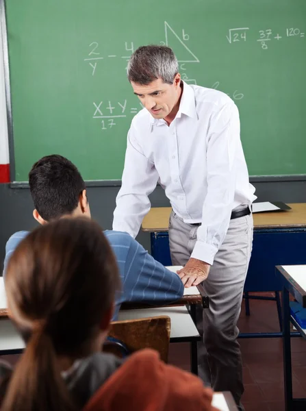 Вчитель допомагає підлітковому школярові на робочому столі — стокове фото