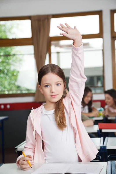 Schoolgirl Raising Hand While Standing In Classroom — Stock Photo, Image