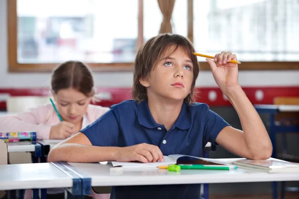 教室で勉強しながら見上げる少年 — ストック写真