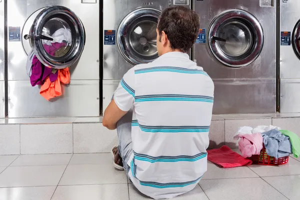 Man Sitting In Front Of Washing Machines Royalty Free Stock Photos