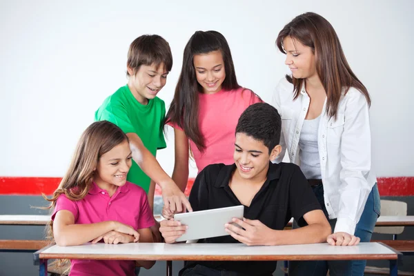 Schoolboy apontando para Tablet com colegas de classe na sala de aula — Fotografia de Stock