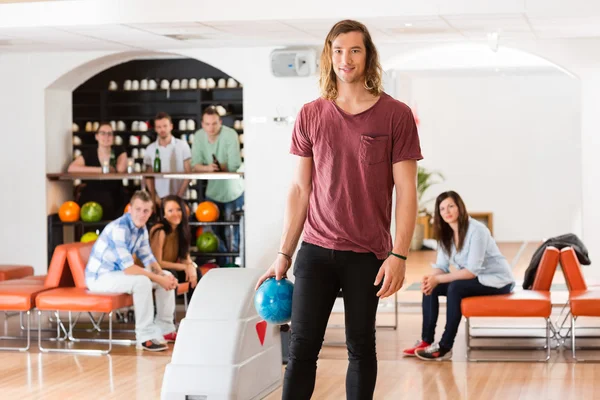 Jovem homem segurando bola no bowling beco no clube — Fotografia de Stock