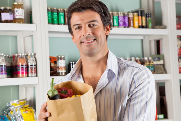 Mannelijke klant met plantaardige tas in supermarkt — Stockfoto