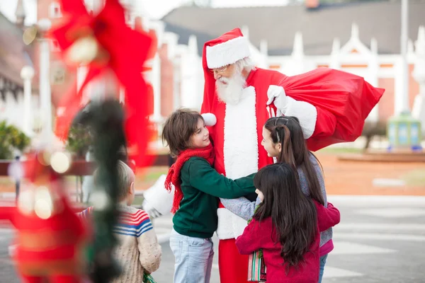 Crianças abraçando Papai Noel — Fotografia de Stock