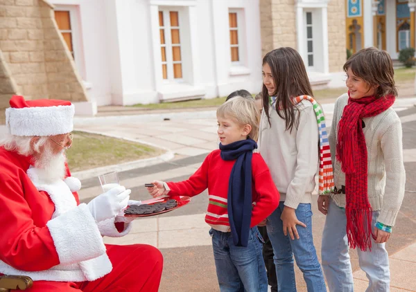 Kinder nehmen Kekse vom Weihnachtsmann — Stockfoto
