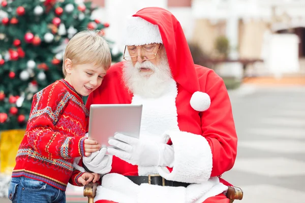 Pojke och jultomten med digital tablet — Stockfoto