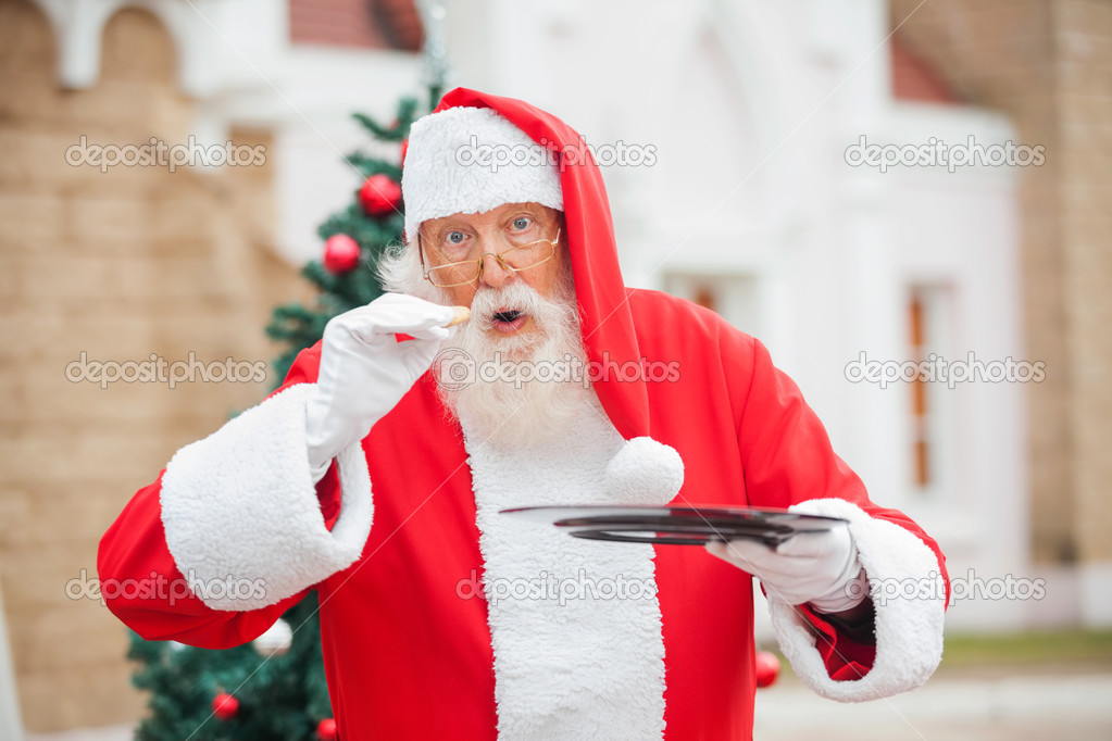 Santa Claus Eating Cookie Against House
