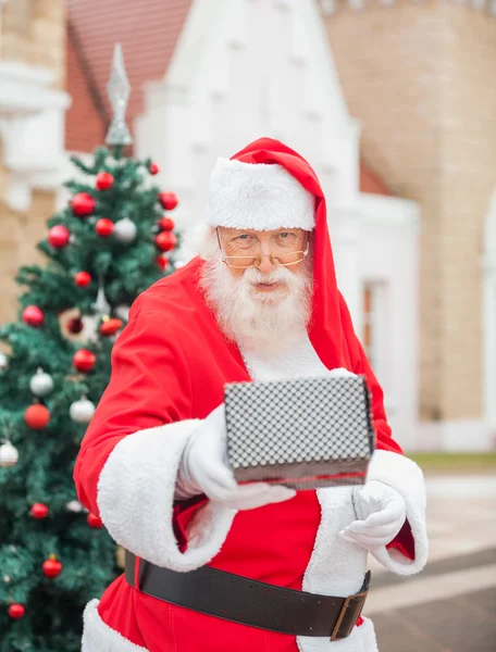 Santa Claus dando regalo contra la casa —  Fotos de Stock