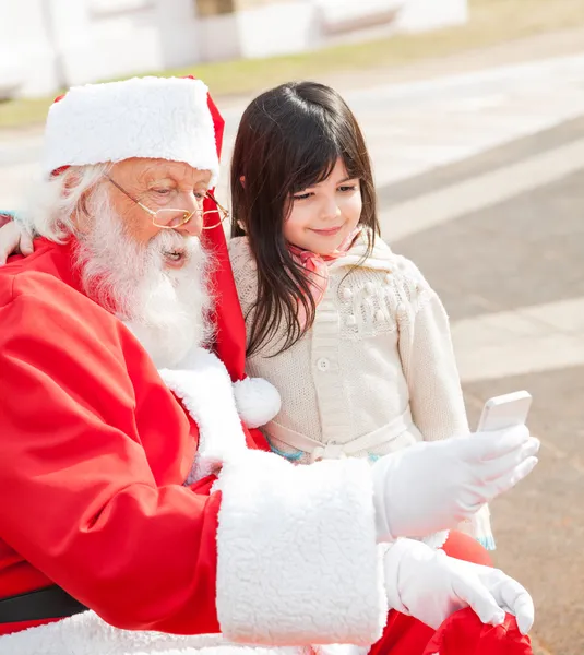 Meisje en santa claus nemen zelfportret via smartphone — Stockfoto