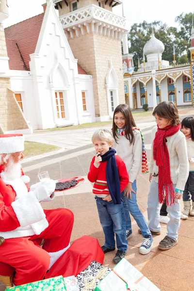 Santa claus oferuje ciastka dla dzieci — Zdjęcie stockowe