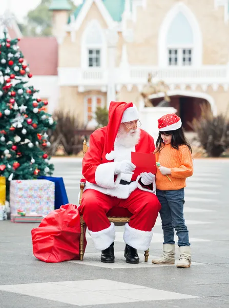 Menina e Papai Noel com carta de desejo — Fotografia de Stock