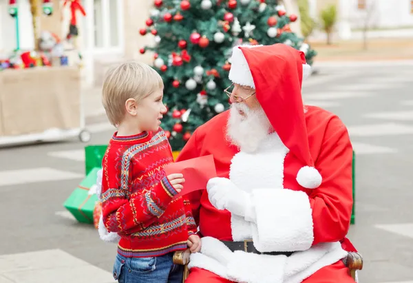 Weihnachtsmann nimmt Wunschzettel von Junge an sich — Stockfoto