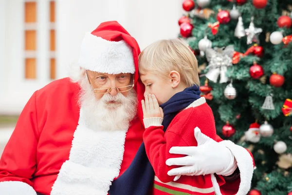 Junge flüstert Weihnachtsmann ins Ohr — Stockfoto