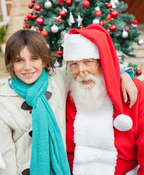 Glücklicher Junge mit Arm um den Weihnachtsmann — Stockfoto