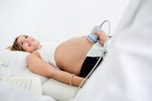 Frau bekommt Ultraschalluntersuchung vom Geburtshelfer
