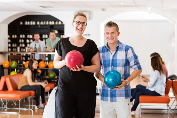 Felice uomo e donna in possesso di palle da bowling nel club — Foto Stock