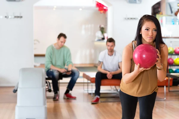 Jeune femme tenant une boule de bowling en club — Photo