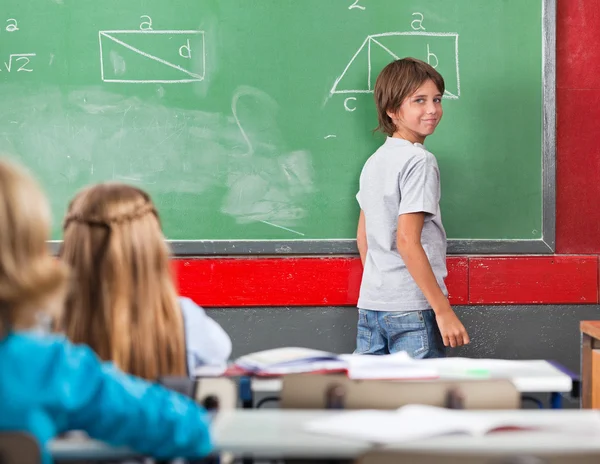 Petit garçon debout près de bord en salle de classe — Photo