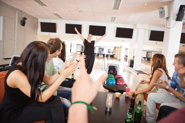 Vrienden applaudisseren voor vrouw in bowlingclub — Stockfoto